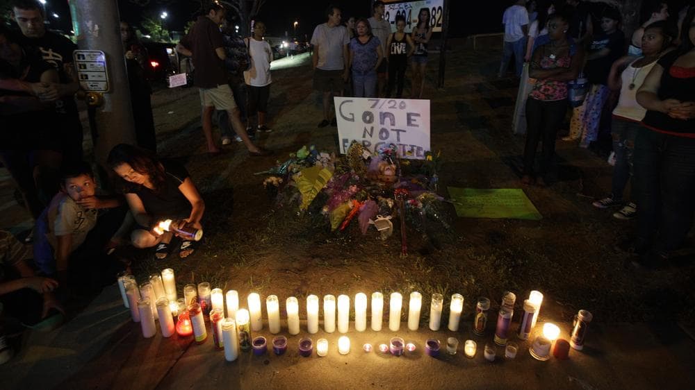 Woman lights candles at a growing memorial across the street from the Century 16 movie theater, late Friday in Aurora, Colo. (AP)