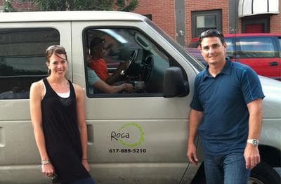 Dana Betts, Roca's director of programming, and Chelsea Police Lt. Ed Conley stand beside the Roca van. Youth workers Zac Rich, near, and Tha Thai sit inside the van. (Deborah Becker/WBUR)