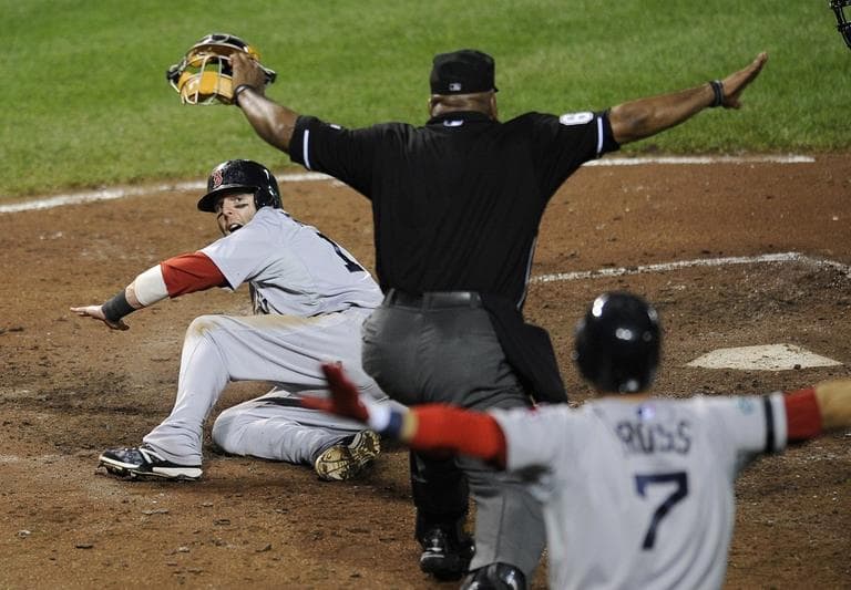 Red Sox's Dustin Pedroia, left, looks up as home plate umpire Laz Diaz, center, and Red Sox's Cody Ross (7) signal "safe" as while scoring on a sacrifice fly by Adrian Gonzalez on Thursday. (AP/Nick Wass)