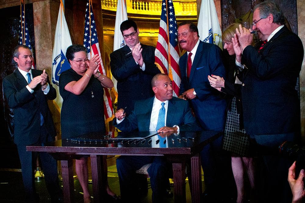 Gov. Deval Patrick is surrounded by government officials and lawmakers as he signs the healthcare cost containment bill into the state capitol on Monday.  (Jesse Costa/WBUR)