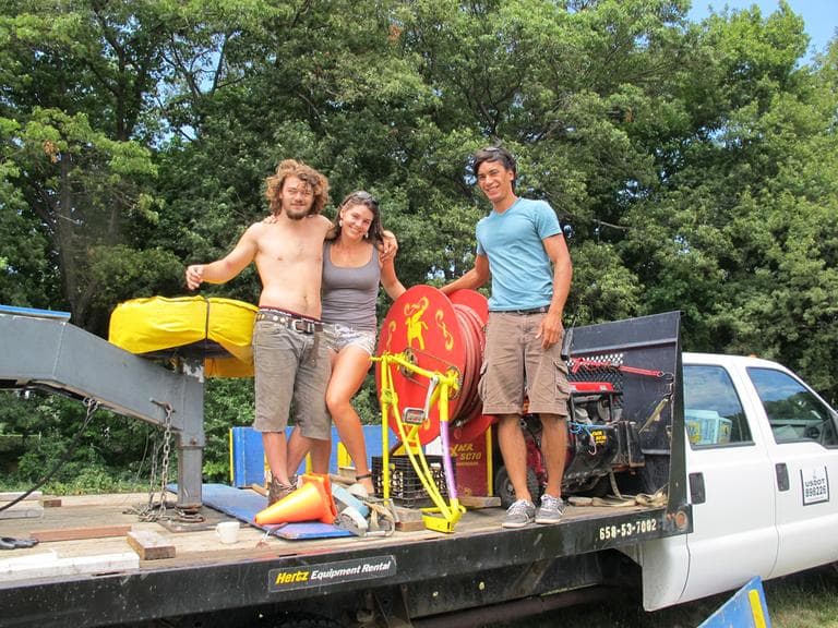 Otto Briner, 19, Hazel Briner, 22, and Andy Marecki, 24, with the hose reel they designed to make raising the big top more efficient. (Andrea Shea/WBUR)