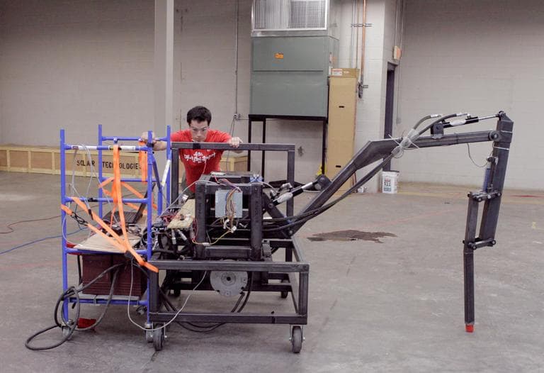 James Whong pushes "Gimpy," a half-scale model of the robotic leg that will be used on the hexapod (Nate Goldman/WBUR)