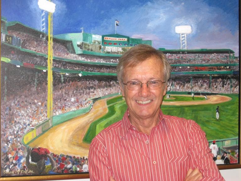 Tony Wheeler, posing in front of a painting of Boston's Fenway Park by Karen McFeaters, at WBUR. (Here & Now/Lynn Menegon)