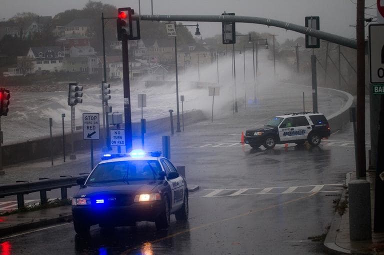 Revere police block Winthrop Parkway as waves crash against the sea wall there. (Jesse Costa/WBUR)