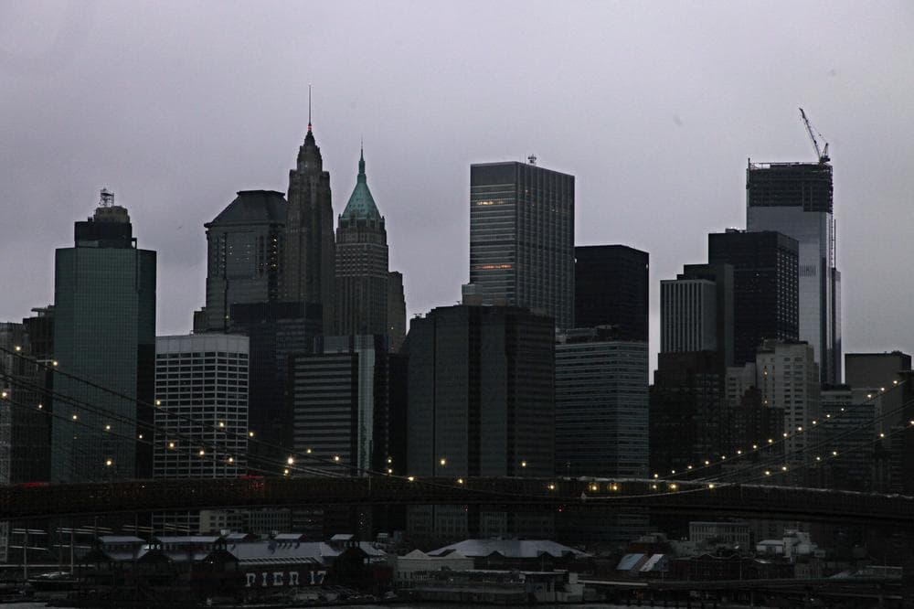 The lights on the Brooklyn Bridge stand in contrast to the lower Manhattan skyline which has lost its electrical supply on Tuesday. (Mark Lennihan/AP)