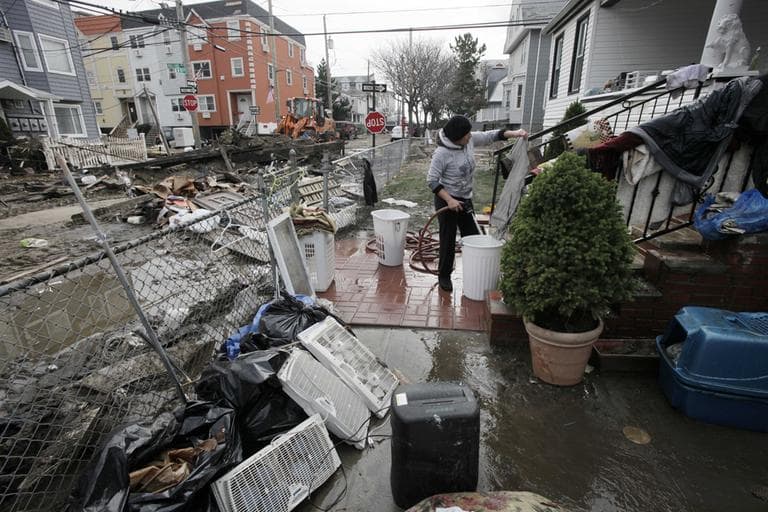 Ruth Dina Ticona washes the mud from clothing damaged by Superstorm Sandy in the front yard of her home in the oceanside community of Far Rockaway, New York, on Thursday. (Mark Lennihan/AP)