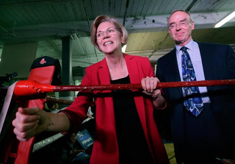 Elizabeth Warren, with her husband Bruce Mann, shakes hands from a boxing ring during a rally at Ramalho's West End Gym in Lowell on Friday. (Elise Amendola/AP)