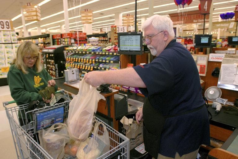 Randy Ritchey loads a plastic bag of groceries into the cart of Marianne Nielsen at the Fred Meyer store in Grants Pass, Ore. in January 2011. (Jeff Barnard/AP)