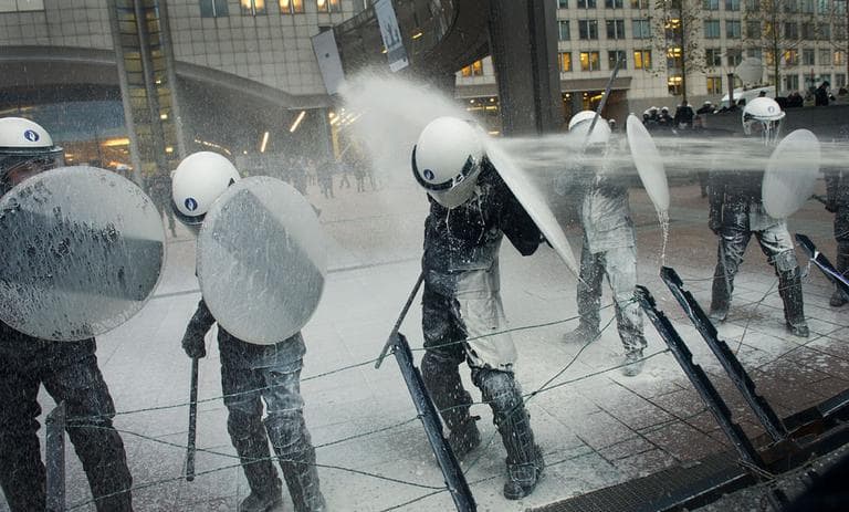 Police officers are sprayed with milk by European milk farmers during a demonstration outside the European Parliament in Brussels, Nov. 26, 2012.  Farmers drove their tractors into the European Quarter of Brussels for a two-day demonstration to protest against what they believe are unfair milk prices. (AP Photo/Geert Vanden Wijngaert)