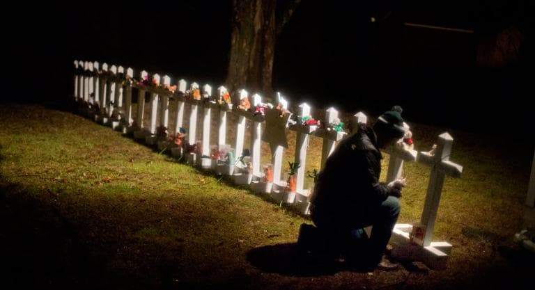 Frank Kulick, adjusts a display of wooden crosses, and a Jewish Star of David, representing the victims of the Sandy Hook Elementary School shooting, on his front lawn, Monday, Dec. 17, 2012, in Newtown, Conn. (AP Photo/David Goldman)