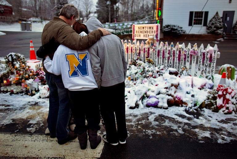 Members of the Rutter family of Sandy Hook, Conn., embrace early Christmas morning as they stand near memorials by the Sandy Hook firehouse in Newtown, Conn. (Craig Ruttle/AP)