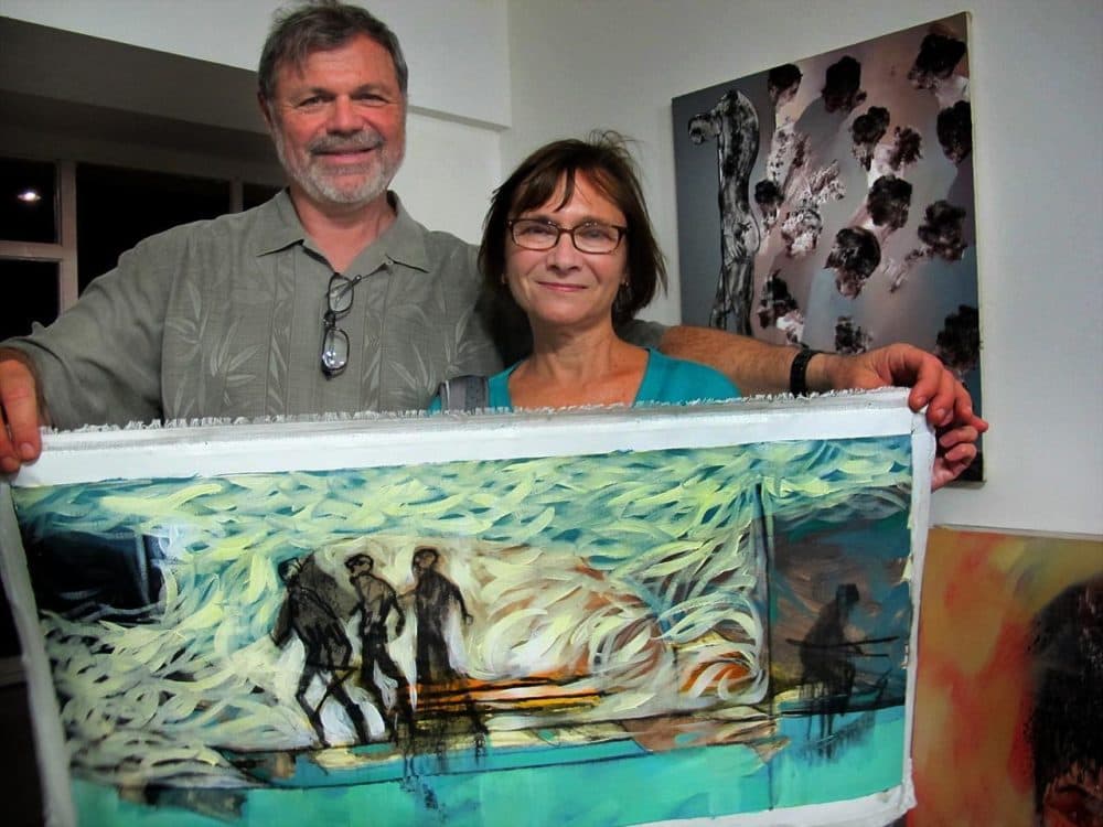 Steve Zelkowitz and Amy Samuelson, of Wellfleet, Mass., hold up one of Edel Bordon’s works they plan to purchase. Together they have bought nine works from Wojcik’s gallery in Provincetown. (Andrea Shea/WBUR)
