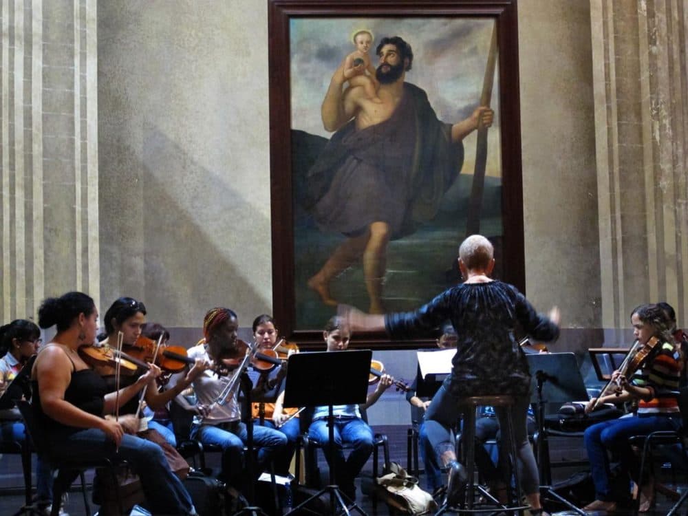 Cuban conductor Zenaida Romeu rehearsing with her all-female orchestra Camerata Romeu in Old Havana’s Basilica of St. Francis of Assisi. (Andrea Shea/WBUR)