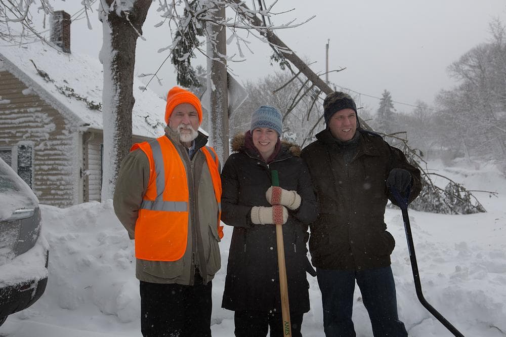 Bob Daly, Natalie and Chris St.George are neighbors on Hull St. on the Hingham and Cohasset border. A tree fell down on a power line, knocking out power on the street. Daly lives in Hingham and the St. Georges live across the street in Cohasset. They were helping each other to shovel snow. Daly says, "It's neighbors helping neighbors." (Jesse Costa/WBUR)