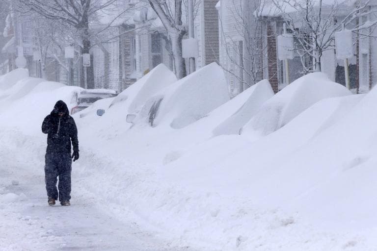  man talks on the phone as he walks along a row of buried cars on Third street in South Boston on Saturday. (Gene J. Puskar/AP)