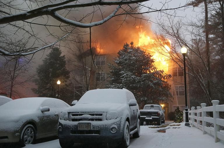Snow-covered cars sit in a parking lot adjacent to where firefighters battle a 4-alarm fire in a 3-story apartment building in Wilmington, Mass., Friday, Feb. 8, 2013. (Elise Amendola/AP)