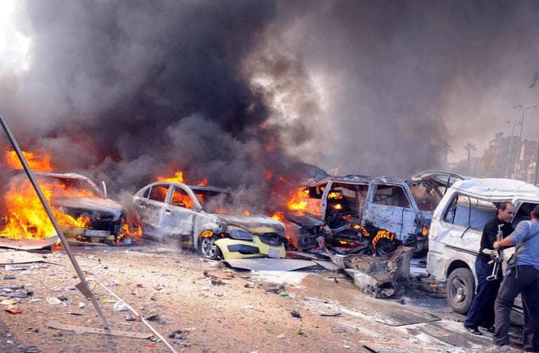 This photo released by the Syrian official news agency SANA, shows Syrian security agents next to a vehicle on fire following a huge explosion that shook central Damascus, Syria, Thursday, Feb. 21, 2013. (AP/SANA)