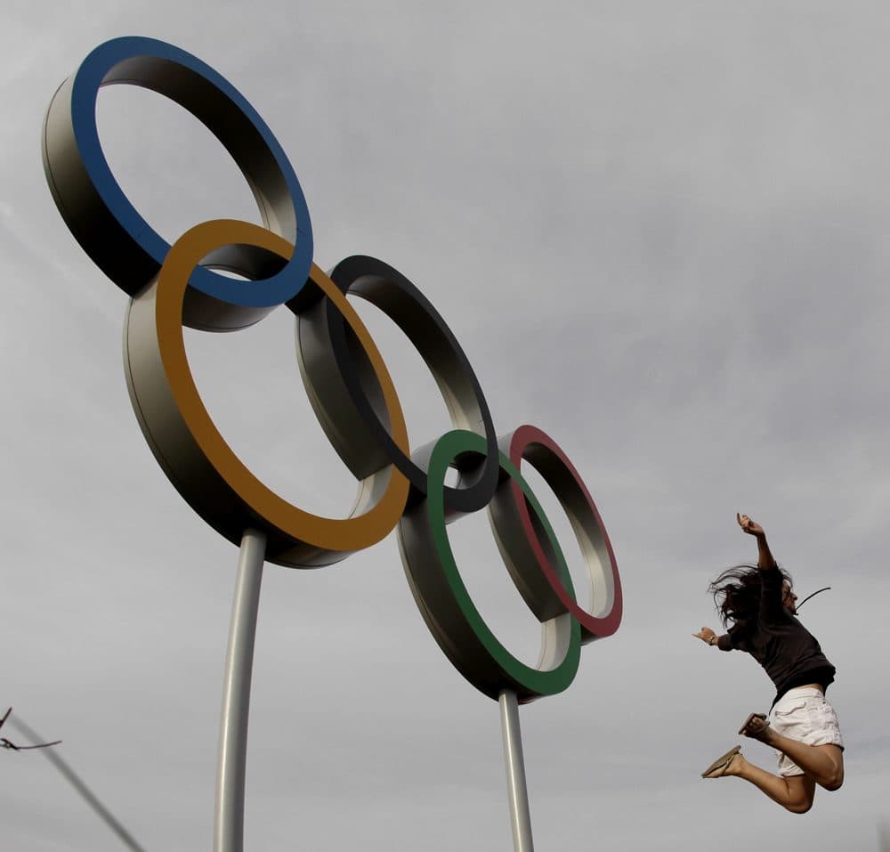A visitor to Olympic Park jumps in the air by a set of Olympic rings at the 2012 Summer Olympics Saturday, Aug. 11, 2012, in London. (Charlie Riedel/AP)