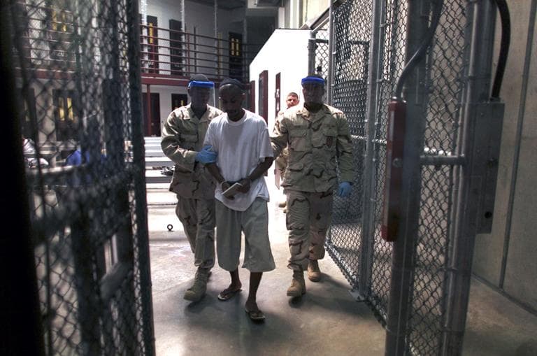 A Guantanamo detainee carries a workbook as he is escorted by guards after attending a class in "Life Skills," inside Camp 6 high-security detention facility at Guantanamo Bay U.S. Naval Base, Cuba, March 30, 2010. Cuba. (Brennan Linsley/AP)