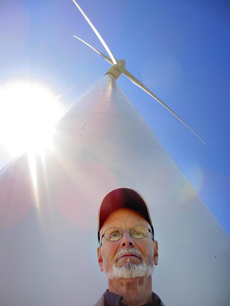 Last year, Malcolm Brown stands under the turbine he helped usher through in Hull. There have been very few complaints about the two turbines in Hull. (Kathleen McNerney/WBUR)