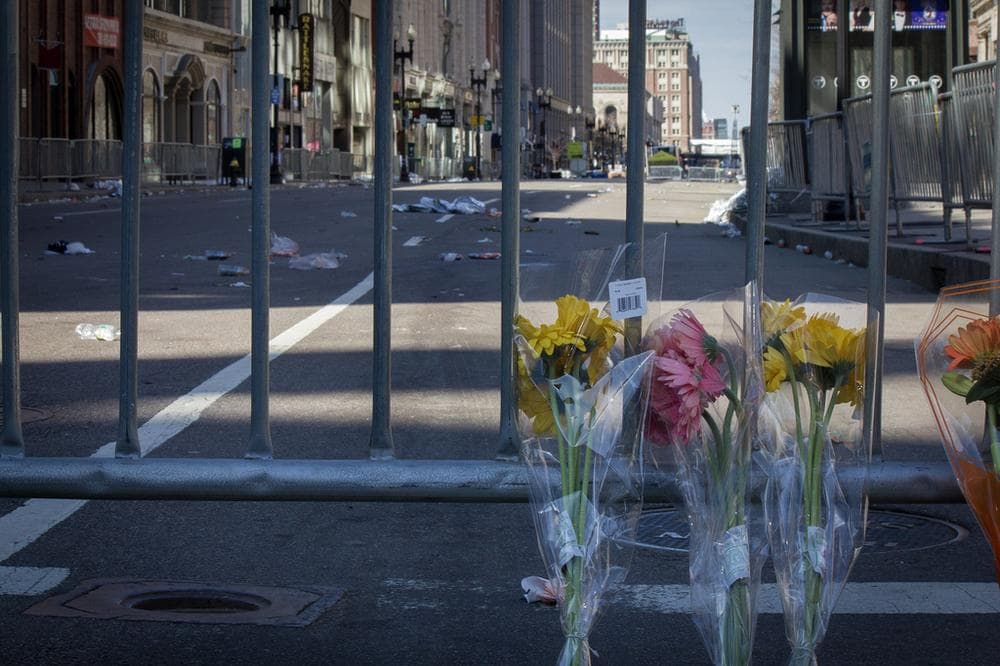 Flowers rest against the barriers blocking access to Boylston Street Tuesday morning. (Joe Spurr/WBUR)