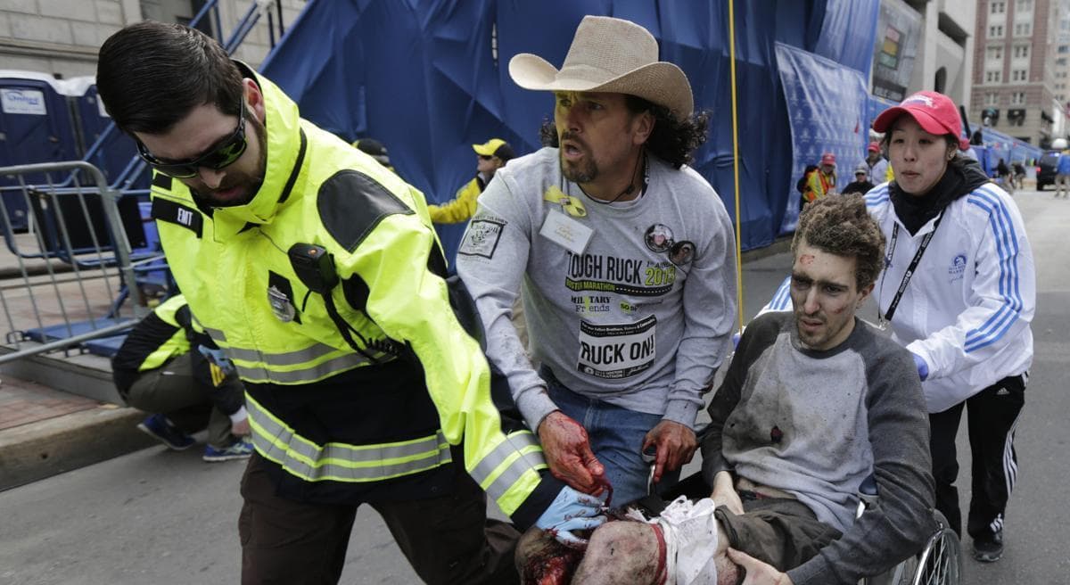 An emergency responder and volunteers, including Carlos Arredondo in the cowboy hat, push Jeff Bauman in a wheel chair after he was injured in an explosion near the finish line of the Boston Marathon Monday, April 15, 2013 in Boston. (Charles Krupa/AP)