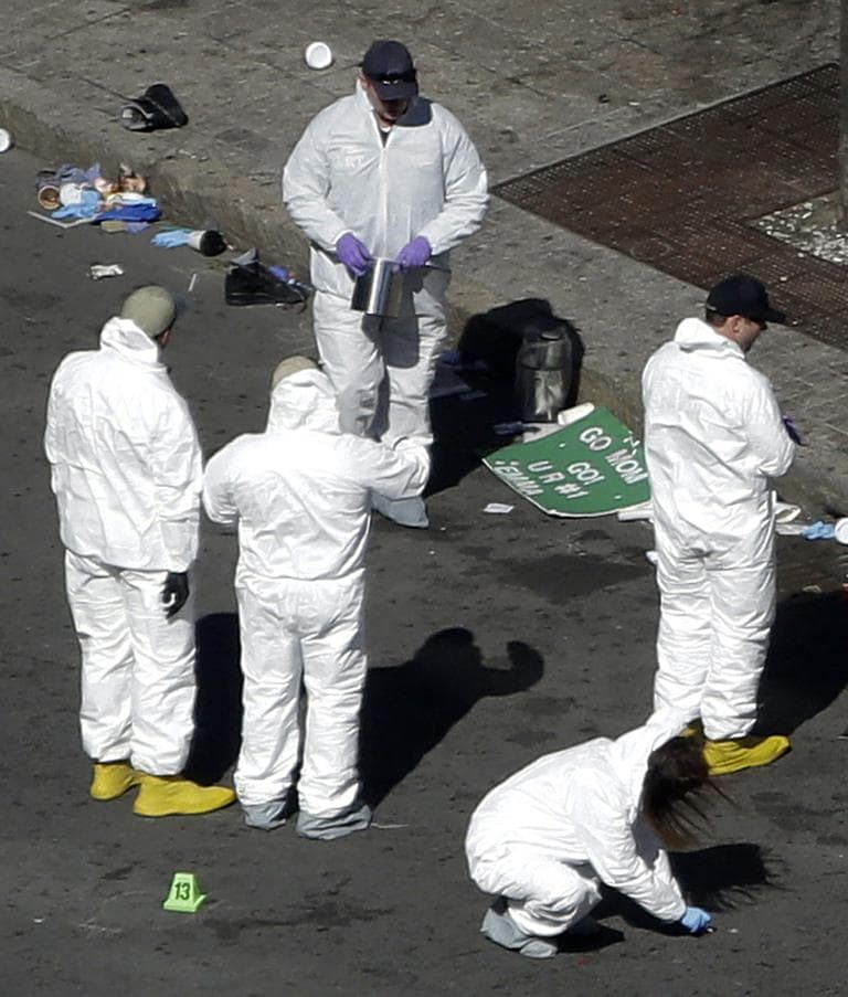 A sign lies on the street as investigators comb through one of the Boston Marathon blast sites on Wednesday. (Julio Cortez/AP)