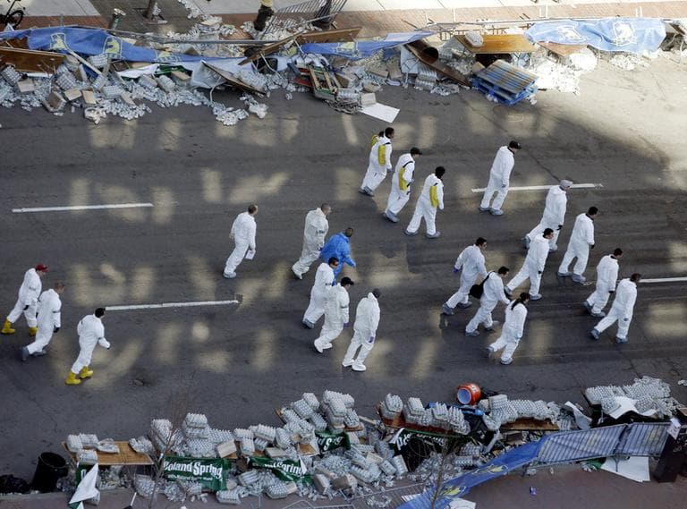 Investigators comb through Boylston Street just beyond the finish line of the Boston Marathon on Wednesday, two days after two bombs exploded.(Julio Cortez/AP)