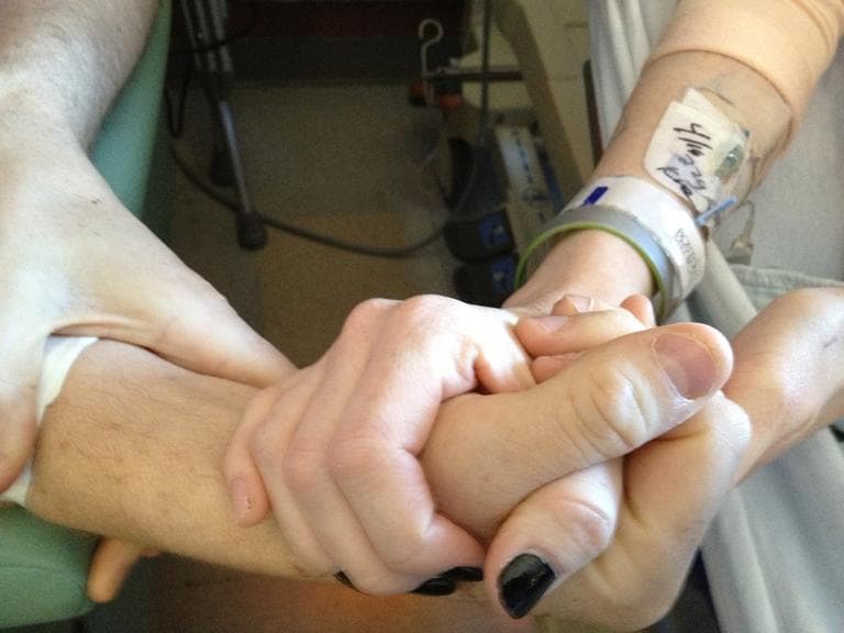 Dancer Adrianne Haslet-Davis and her husband, Air Force Capt. Adam Davis, hold hands at Boston Medical Center on Sunday. (Robin Young/Here &amp; Now)
