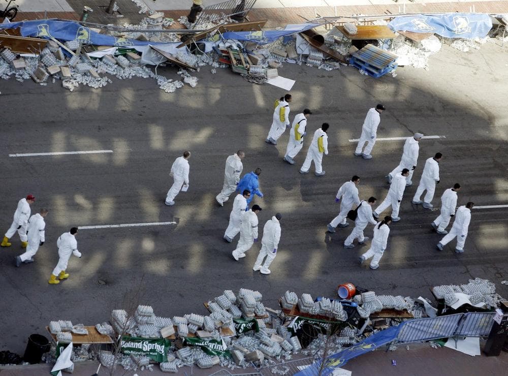 Investigators comb through Boylston Street just beyond the finish line of the Boston Marathon, two days after two bombs exploded, Wednesday, April 17, 2013, in Boston.  Authorities investigating the deadly bombings have recovered a piece of circuit board that they believe was part of one of the explosive devices, and also found the lid of a pressure cooker that apparently was catapulted onto the roof of a nearby building, an official said Wednesday.(AP Photo/Julio Cortez)