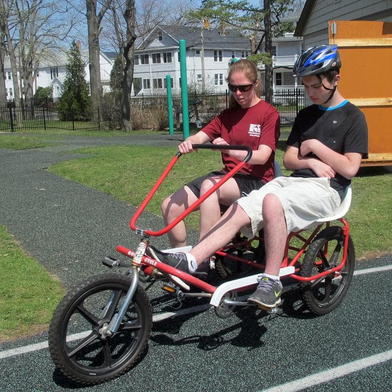 Michael, 15, rides a tandem bicycle with instructor Mary Gavin. (Andrea Shea/WBUR)