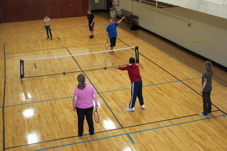 Visually-impaired students play tennis with the help of instructors and specially designed balls. (Andrea Shea/WBUR)