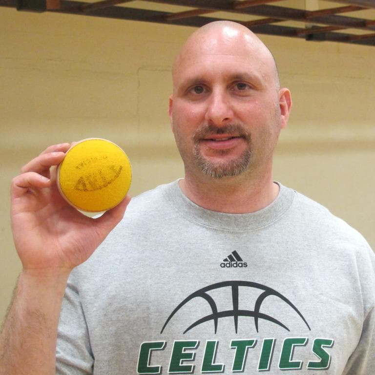 Perkins adaptive P.E. coordinator Matt LaCortiglia holds up a specially designed tennis ball with BBs inside. (Andrea Shea/WBUR)