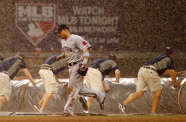 Red Sox right fielder Shane Victorino (18) runs to the dugout as grounds crew tarp the field during a rain delay. (AP/Genevieve Ross)