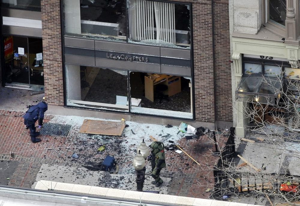 Officials wearing protective suits investigate one of two blast sites near the finish line of the 2013 Boston Marathon after explosions shook the area on Monday, April 15, 2013 in Boston. (Elise Amendola/AP)