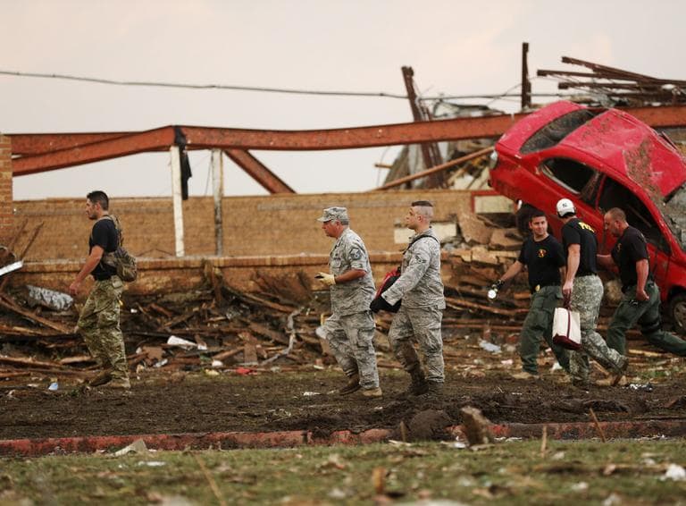 Workers walk through the rubble of the Plaza Towers Elementary School. Kindergarten through 3rd students grade took shelter in the Plaza Towers Elementary School basement while 4th, 5th and 6th graders were evacuated. At least seven students are among the dead. (Sue Ogrocki/ AP)
