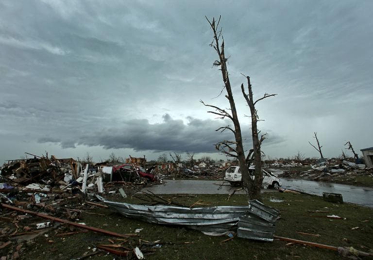 Storm clouds build in the distance as in Moore residents clean up after Monday's tornado. (Charlie Riedel/ AP)