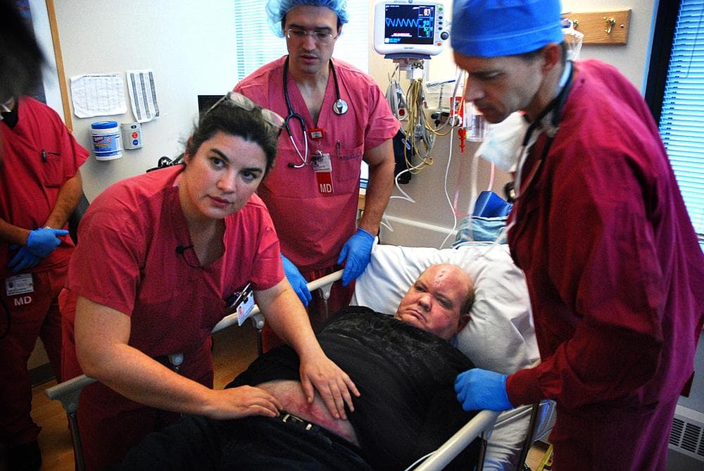 Surgeon Susannah Rowe, anesthesiologist Oleg Gusakov, M.D. and nurse anestheticst Dale Putnam, CRNA, prepare Kevin for surgery. (George Hicks/WBUR)