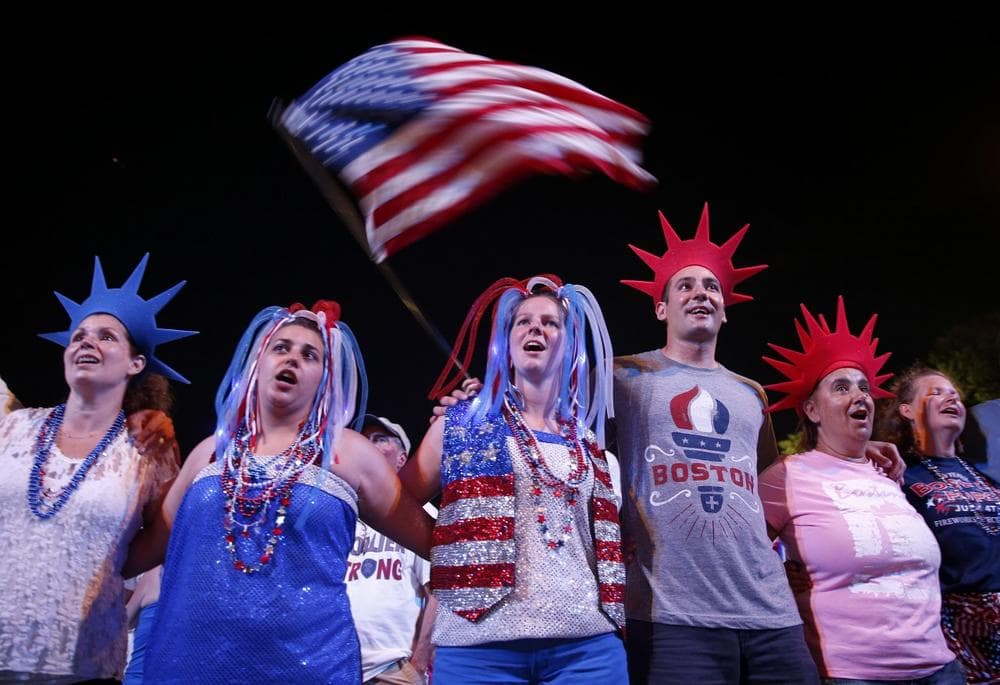 Audience members join arms as the Boston Pops play &quot;God Bless America&quot; during their Fourth of July Concert at the Hatch Shell in Boston, Thursday, July 4, 2013. (AP/Michael Dwyer)