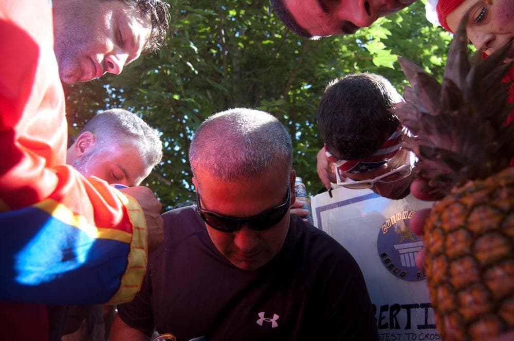 Eight-time Greasy Pole-walking champ Peter Frontiero (in black shirt) leads costumed walkers in a prayer in his backyard before they head down to the waterfront to compete on Saturday evening. (Greg Cook)