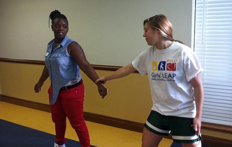 Monique Blocker, a violence intervention/prevention youth leader for the Madison Park Development Corporation in Roxbury, learns a wrist breakaway from a Girls' LEAP volunteer. (Delores Handy/WBUR)