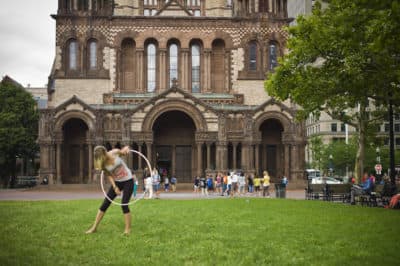 A woman practices a hula hoop routine in front of the Trinity Church on Copley Square. (Dominick Reuter for WBUR)