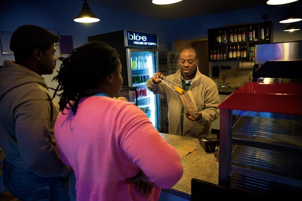 Calixte Dorisca serves up an order of chicken patés at the Blue House of Coffee on Blue Hill Avenue, which he opened last April. (Jesse Costa/WBUR)