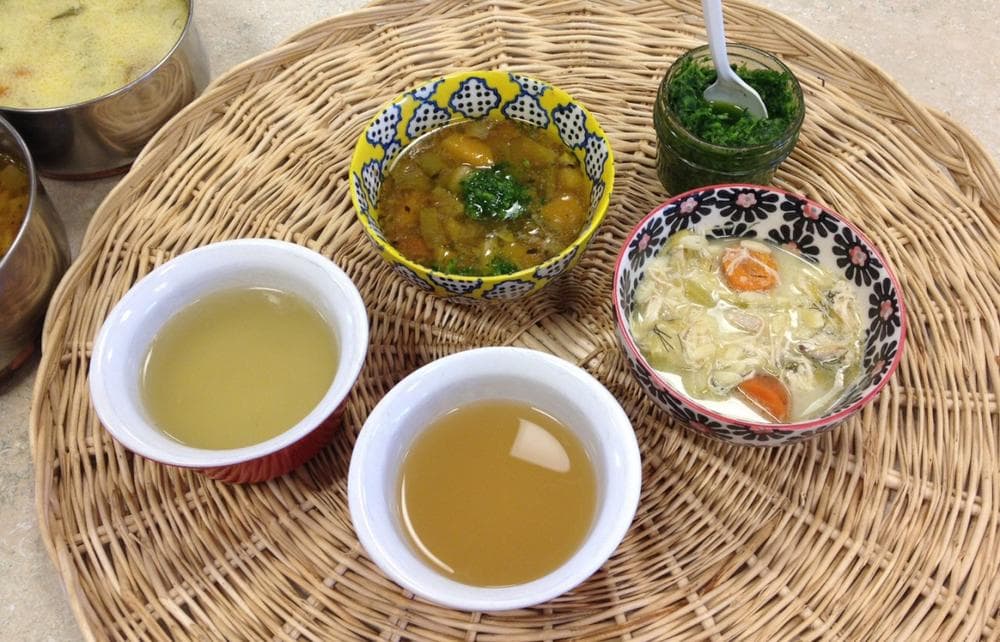 Clockwise from top: Kathy Gunst's Roasted Fall Vegetable Soup, Winter Parsley Pesto, Greek-Style Turkey-Lemon-Rice Soup ("Avgolemono"), store-bought chicken stock and homemade chicken stock. (Rachel Rohr/Here &amp; Now)