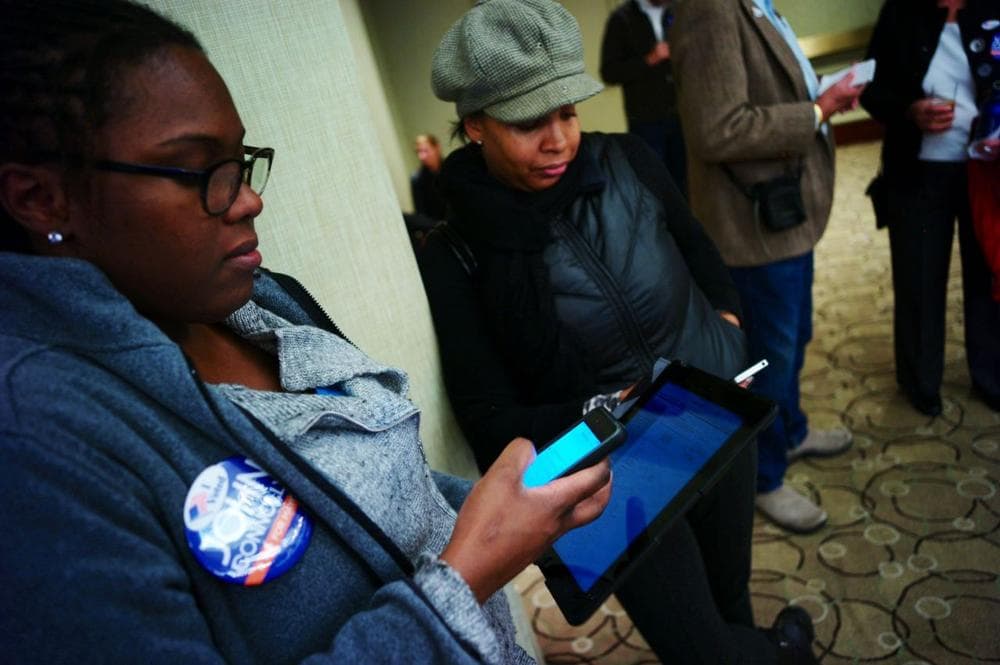 Connolly supporters Sydney Janey and Kai Grant check their devices for early poll results. (Dominick Reuter/WBUR)