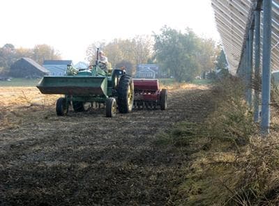 Christian Stanley plants grain on a farm field in Hadley. (Nancy Eve Cohen for WBUR)