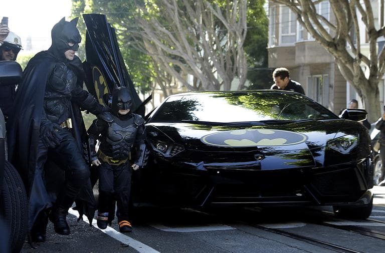 Miles Scott, dressed as Batkid, second from left, exits the Batmobile with Batman to save a damsel in distress in San Francisco Friday. (Jeff Chiu/AP)