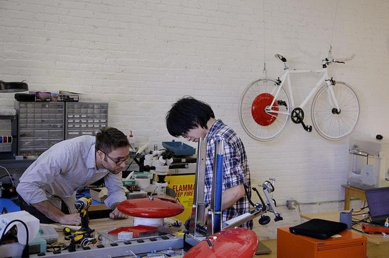 Mechanical and software engineer Julian Fong, right, and vehicle design engineer Jon Stevens work on a development to the Copenhagen Wheel, a human/electric hybrid bicycle engine at Superpedestrian in Cambridge. (Stephan Savoia/AP)