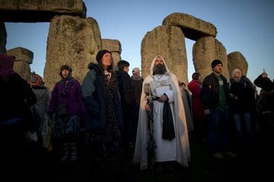 A druid watches the sunrise by the ancient stone circle of Stonehenge, in southern England, as access to the site is given to druids, New Age followers and members of the public on the annual Winter Solstice, Friday, Dec. 21, 2012.