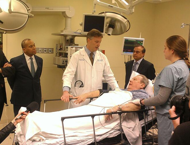 A man lies on a hospital bed as part of a simulation to demonstrate the benefits of expanding the Massachusetts Health Information Highway. (Alec Loftus, of the Department of Health and Human Services, via Twitter)